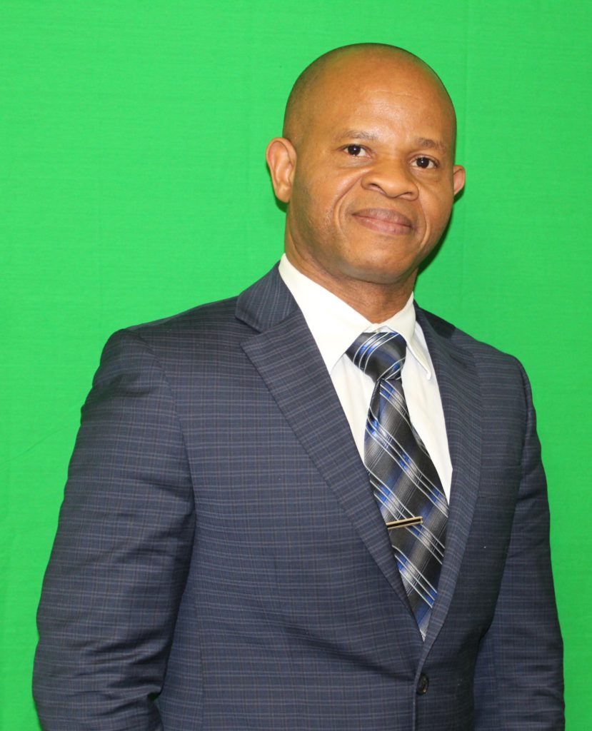 A photo of a person wearing a black suit and a necktie